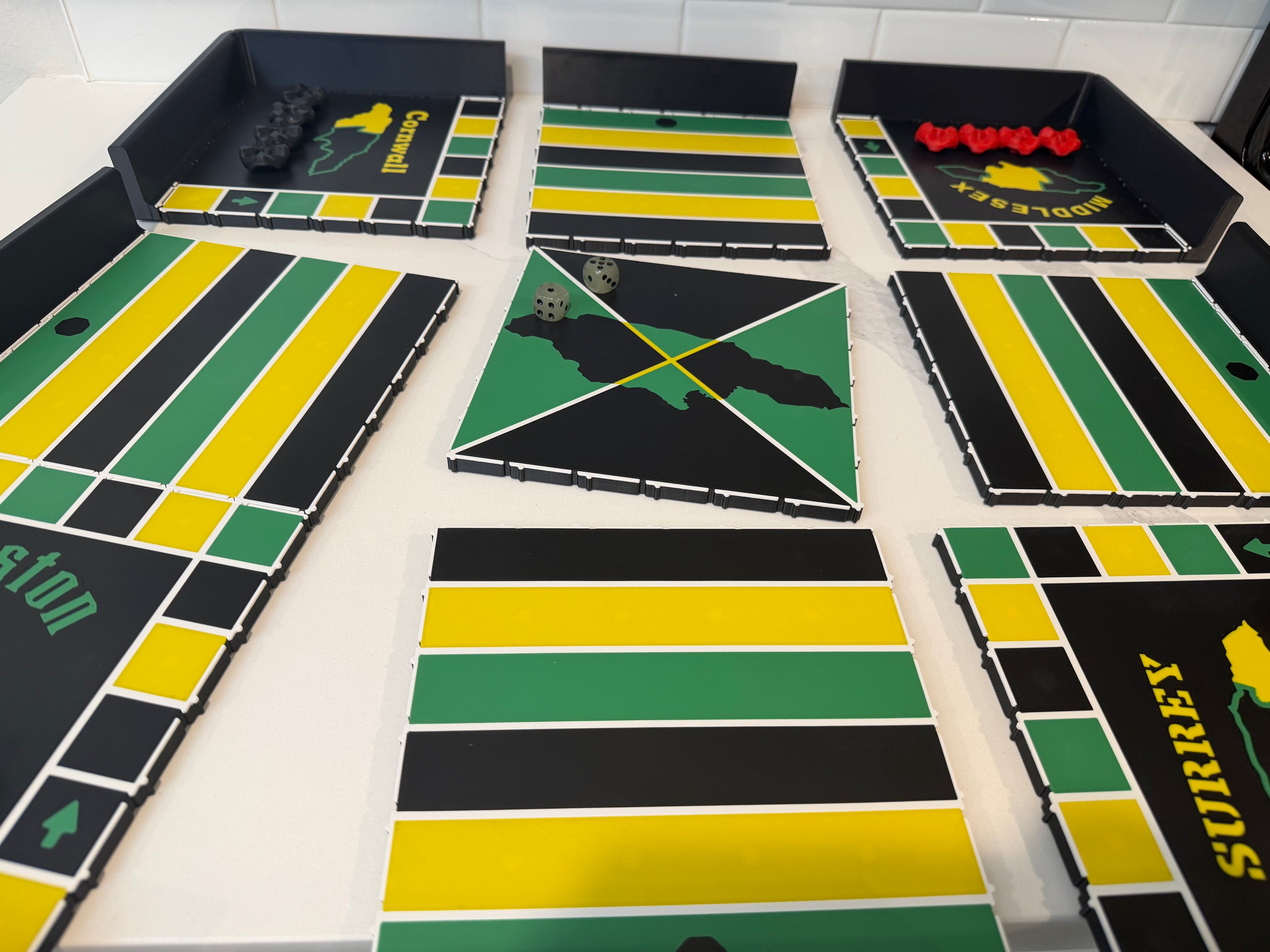 All modular sections of the 24x24-inch magnetic Jamaican Ludi board displayed before assembly, showcasing precision-fit snap-together panels, magnetic side trays, center tile, and durable ASA construction for easy transport and setup.
