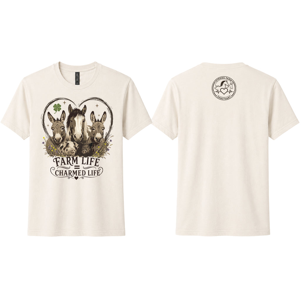Natural Next Level 6410 sueded t-shirt shown from the front and back. The front features a vintage-style "Farm Life Charmed Life" graphic with rescued donkeys, a horse, heart outline, clover, and wildflowers. The back includes the Strong Farm Sanctuary logo printed below the collar.