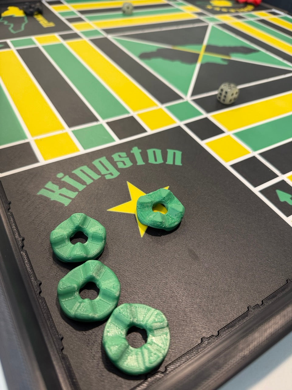 Four green game pieces in the Kingston corner of the 24-inch non-magnetic Lock Pon Stop Jamaican Ludi board.