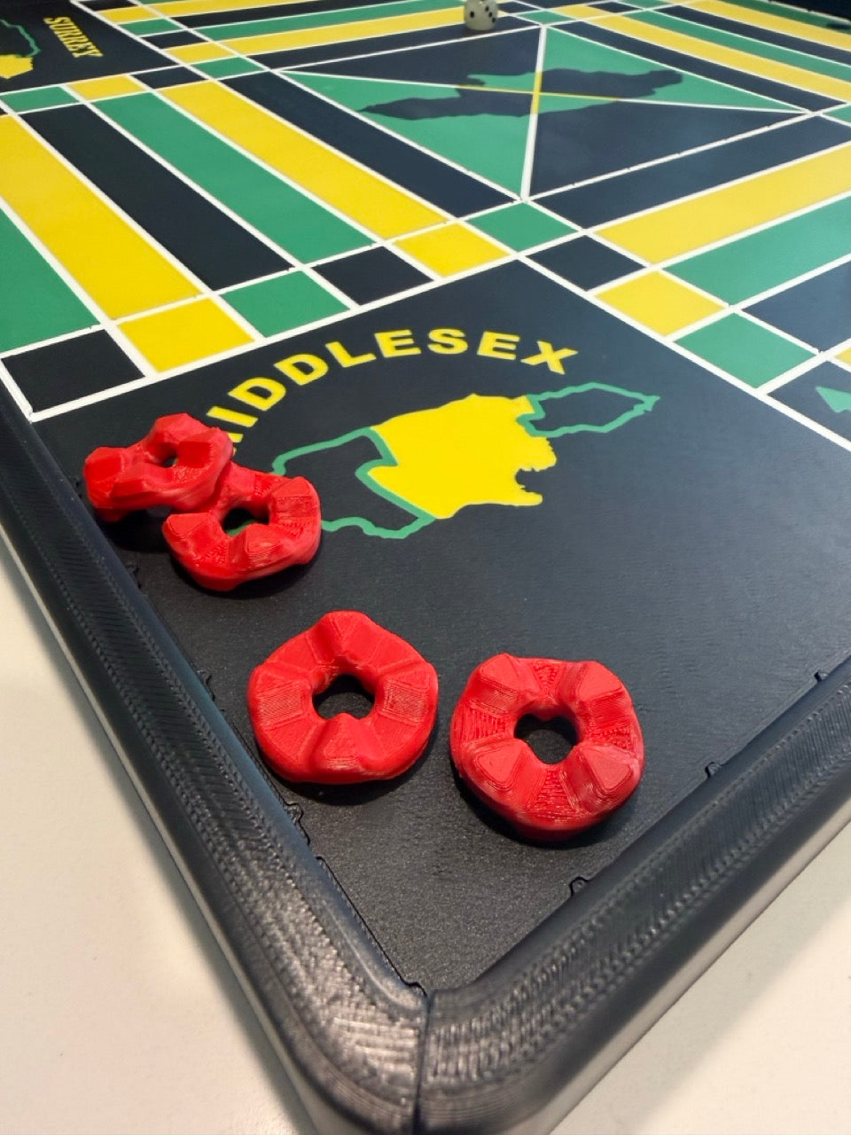 Four red game pieces in the Middlesex corner of the 24-inch non-magnetic Lock Pon Stop Jamaican Ludi board.