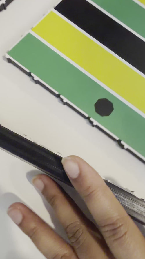 Close-up video of hands assembling a premium 24x24-inch modular magnetic Jamaican Ludi board by attaching a border piece with built-in magnets. The snap-together design demonstrates quick setup and durable construction.
